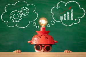 child with silly light bulb hat on, sitting in front of a chalkboard, representing how kids have fun during private tutoring at Fit Learning in St. Louis