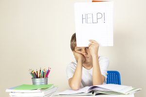 Depressed-looking young boy holding a HELP sign is a great candidate for special needs tutoring at Fit Learning in St. Louis.