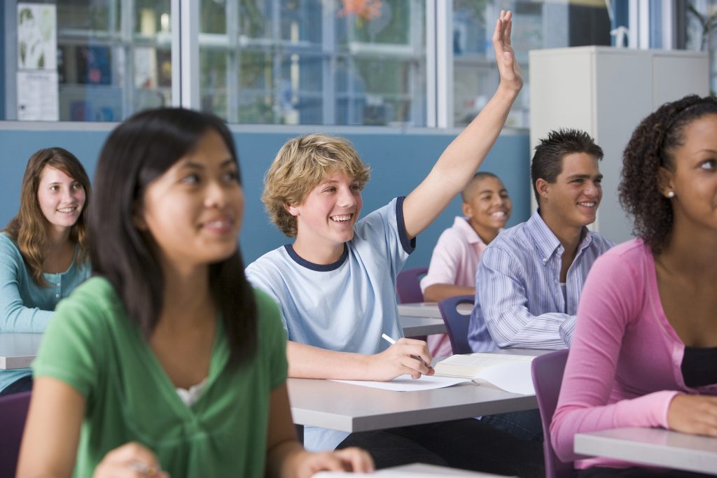 confident teen boy with ADHD raises his hand in class. He got ADHD tutoring for math and reading in Creve Coeur at Fit Learning St. Louis 63141