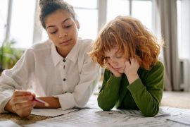 boy with red hair sits at table with learning coach during Fit Learning tutoring session