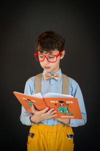 boy wearing glasses reading a book using improved comprehension skills from Fit Learning St. Louis