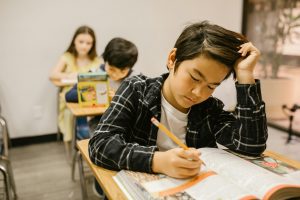 middle school boy in classroom looks discouraged while struggling to complete school work