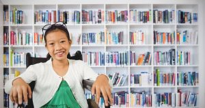 10 year old girl smiling confidently in front of bookshelf after reading fluency tutoring at Fit Learning St. Louis