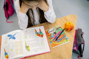 3rd grade reading tutor St. Louis | alternative reading instruction in St. Louis | fluency training for elementary age student | evidence based reading program for kids | st. louis reading tutor 3rd grade girl looks down at her desk and schoolwork, appearing overwhelmed and in need of reading tutoring to help her catch up to grade level