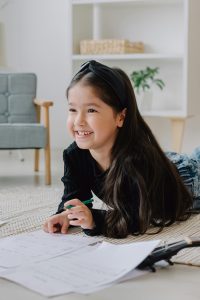 happy girl with long hair looks up smiling as she works on her math homework