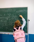 girl with a pink backpack works math problems on chalkboard, no longer plagued with math anxiety after tutoring at Fit Learning St. Louis