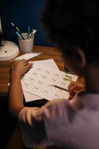 mathematics anxiety in child | tutoring for struggling students | boost child's math confidence | math anxiety strategies for parents | elementary school math anxiety | 63005 | 63146 over-the-shoulder view of a boy doing a math worksheet, much easier now that he's conquered math anxiety through precision teaching at Fit Learning