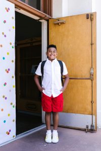 academic summer camp in MO | dyslexia tutor | tutoring | ADHD summer program St. Louis | processing speed help | cognitive skills summer camp | St. Louis, MO | 63131 | 63105 | 63122 proud boy standing outside school smiling and confident after attending academic summer camp at Fit Learning