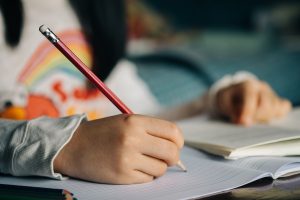 Hand of a student holding a pencil and writing on a piece of paper