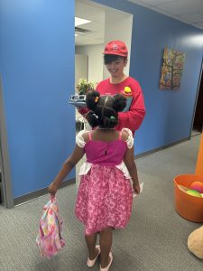 A Fit Learning student attending summer camp wears a costume while looking up and smiling at her learning coach, who also wears a costume