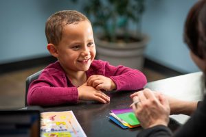 Young boy smiles across the table at his Fit Learning tutor during a fun, fast-paced remediation session