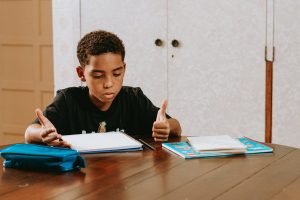 Middle school boy working on homework gestures looks frustrated and confused