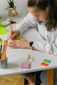 Student sitting at a desk writes on a sticky note to help keep organized