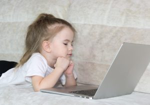 Young girl relaxes on a couch while looking at her tablet